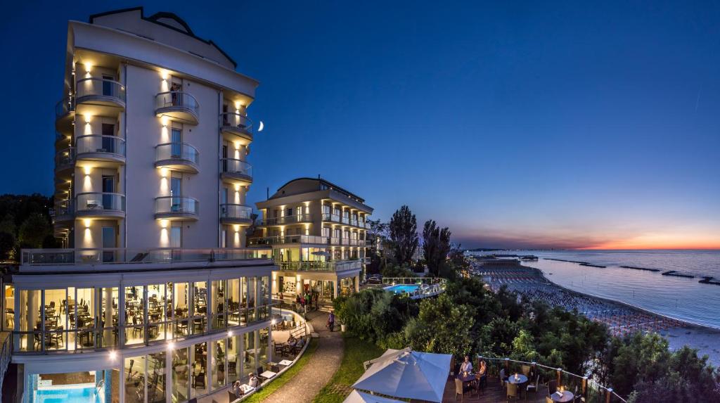 a large building next to a beach at night at Hotel Sans Souci in Gabicce Mare