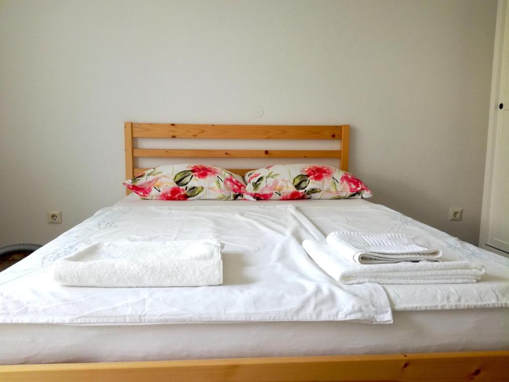 un letto con lenzuola e cuscini bianchi e asciugamani di Bright Side Studios - self check-in a Lubiana