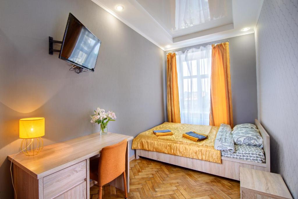 a small bedroom with a bed and a desk and a television at Premium Hostel in Lviv