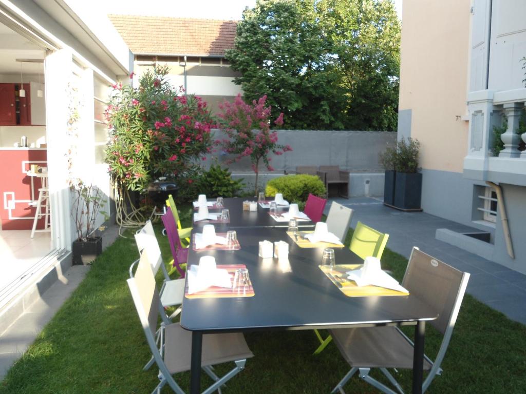 a patio with a table and chairs on the grass at Chambres d'Hôtes Les Muriers in Romans-sur-Isère