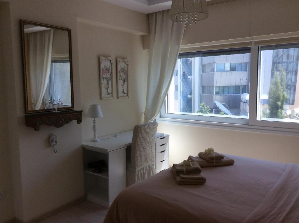 1 dormitorio con cama, escritorio y ventana en The Central Suites en Nicosia