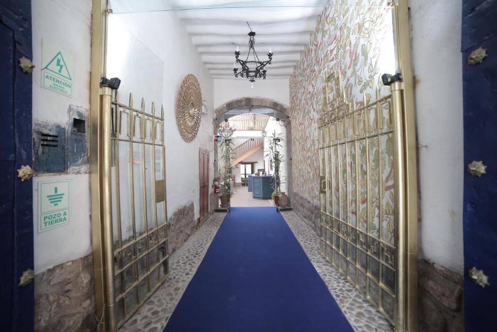 einen Flur mit blauem Teppich in einem Gebäude mit Toren in der Unterkunft Posada Villa Mayor in Cusco