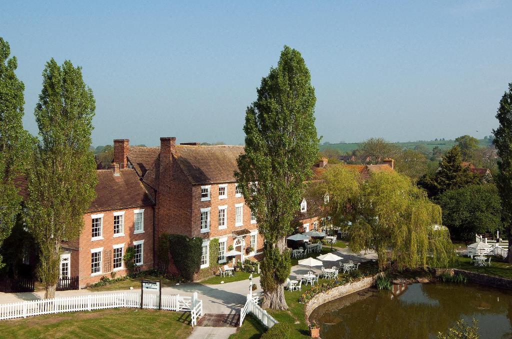 a large brick building with a pond in front of it at Corse Lawn House Hotel in Corse