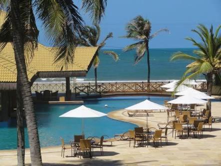 a pool with chairs and umbrellas next to the ocean at Fleixeiras Eco Residence in Trairi