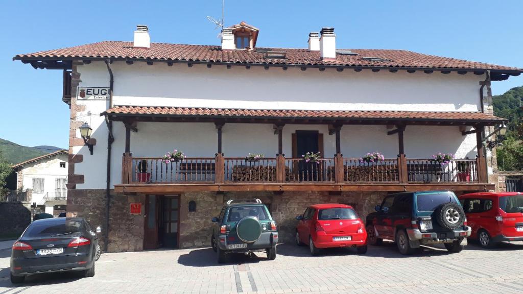Casa Martiko في Eugi: مبنى فيه بلكونه فيه سيارات تقف امامه