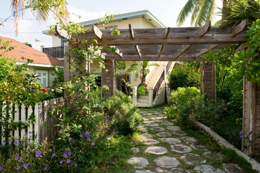 a wooden pergola in a garden with flowers at The Sugar Apple Lodging in Harbour Island