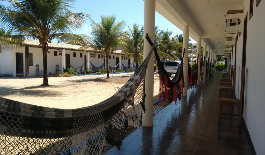 a hammock on the side of a building next to a beach at Pousada Hawai in Conde