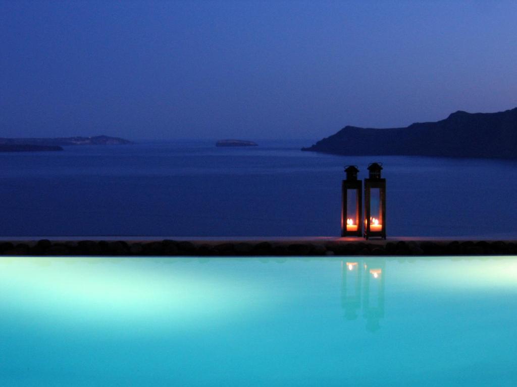 two candles sitting next to a swimming pool at night at Grand Canava in Oia