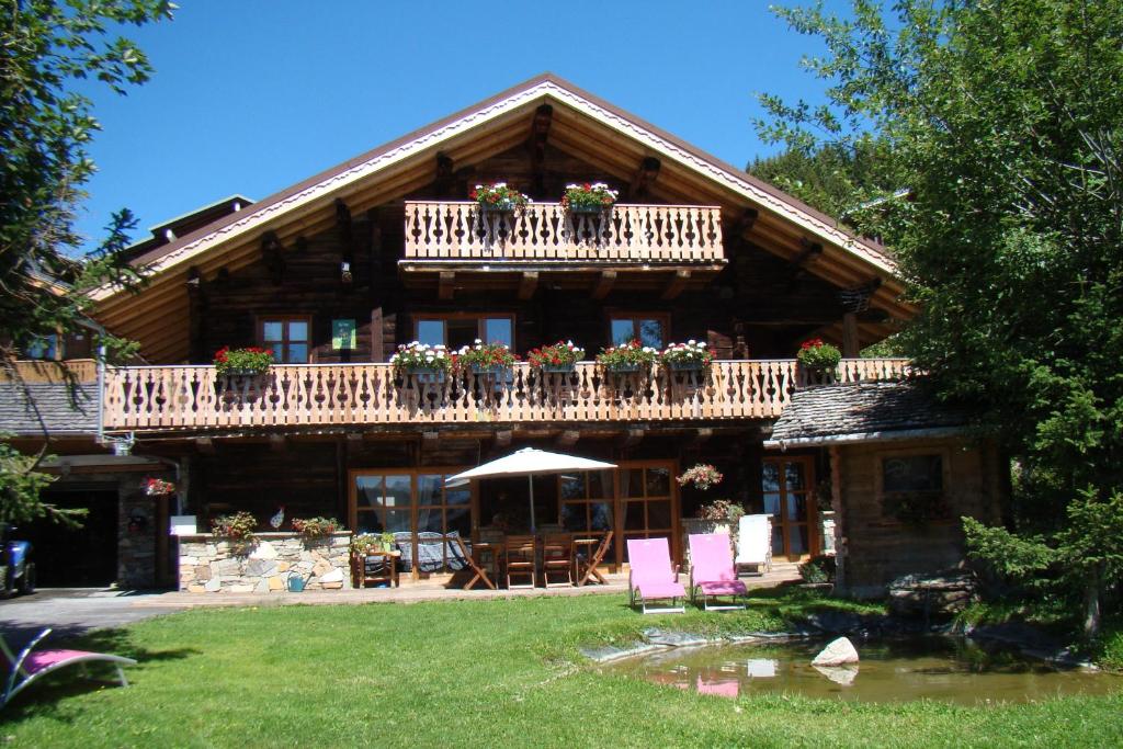 Casa de madera con balcón, mesas y sillas en Chalet 13 personnes-Le Vanvolet en Les Saisies