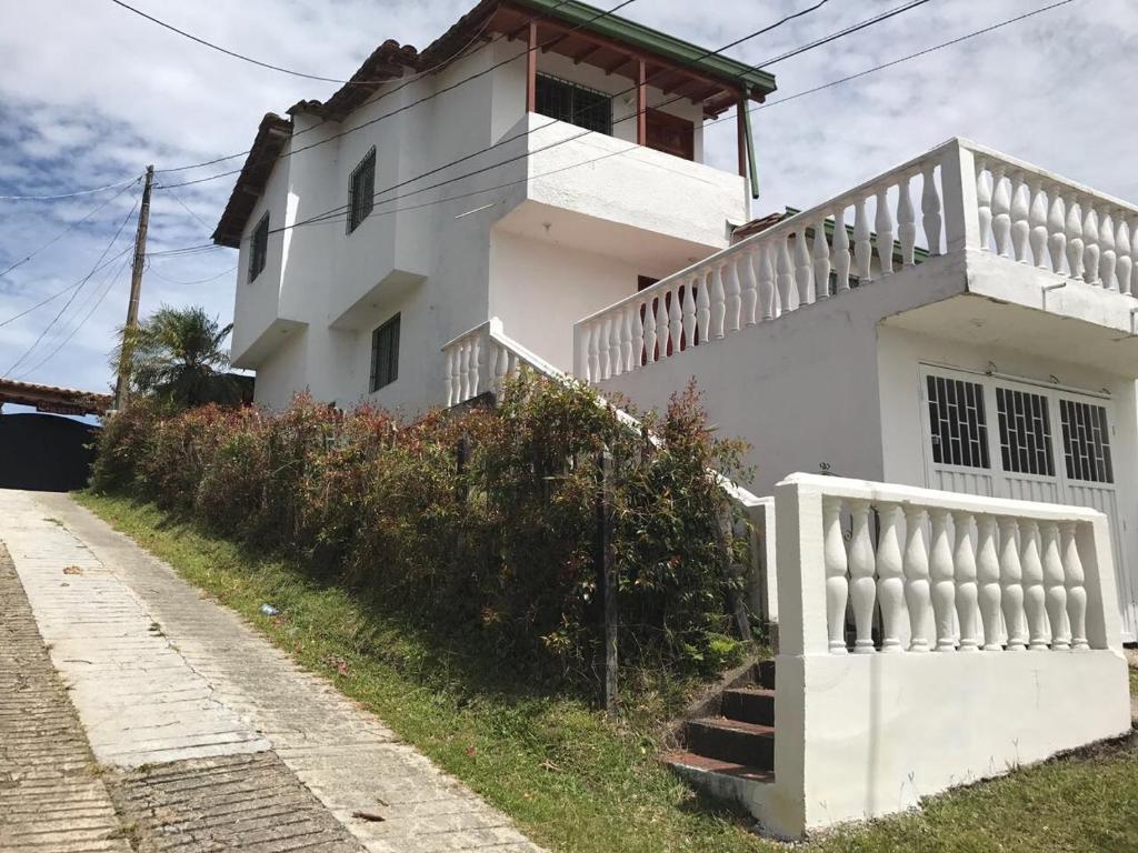 a white house with a staircase next to a street at Cabaña El Roble in Guatapé