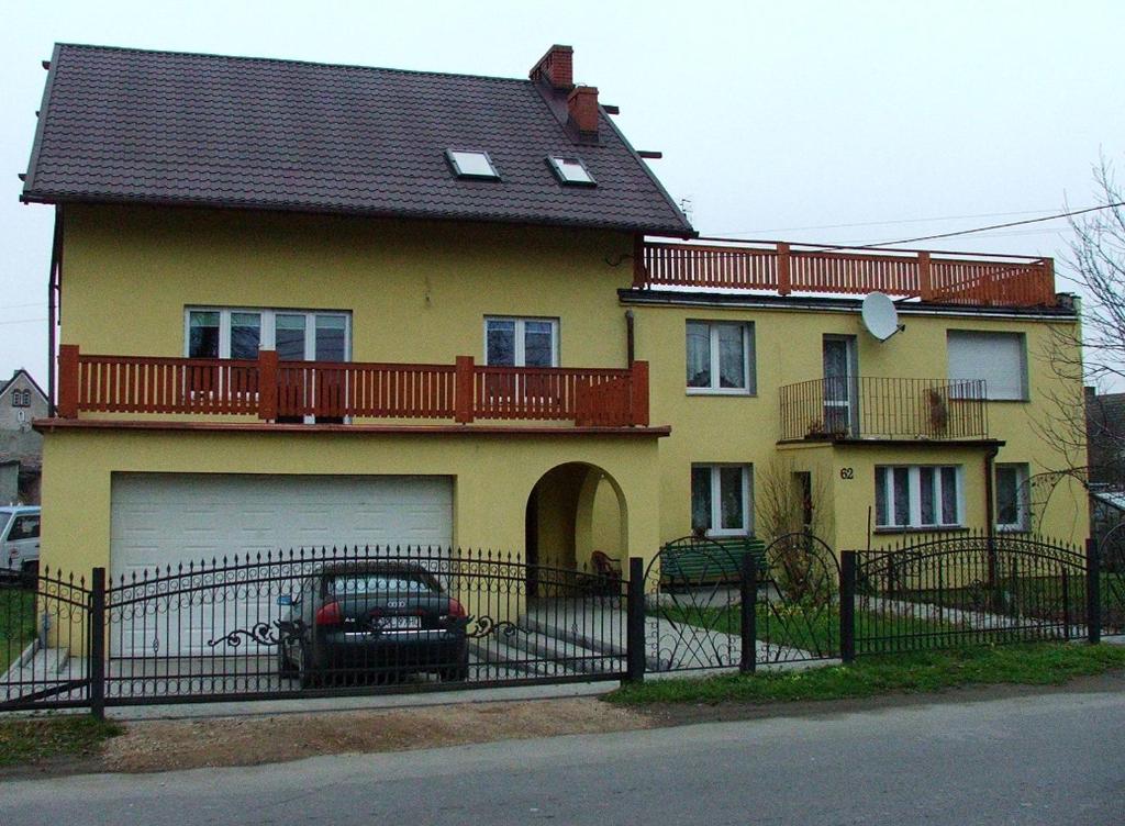 a yellow house with a car parked in front of it at Pokoje Gościnne, Kudowa-Słone 62 in Kudowa-Zdrój