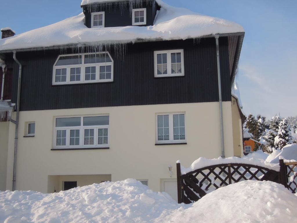 una casa cubierta de nieve con techo negro en Am Dürrenbachtal, en Klingenthal
