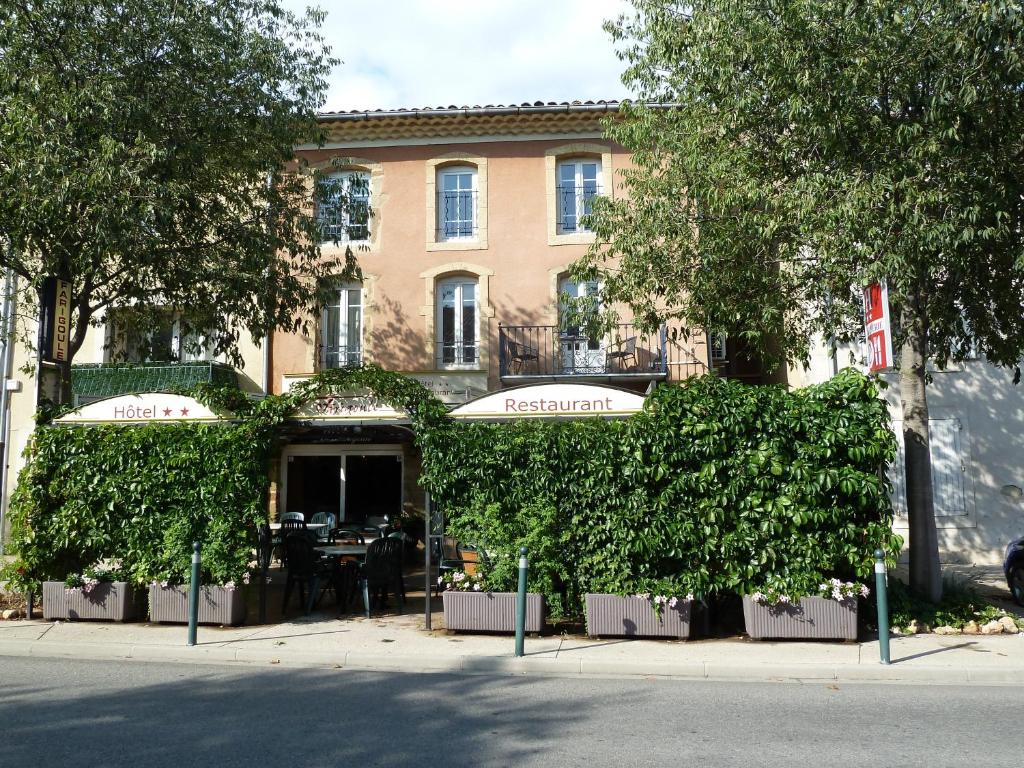 Logis Hôtel Restaurant La Farigoule في Sainte-Cécile-les-Vignes: مبنى فيه اللبي ينمو امامه