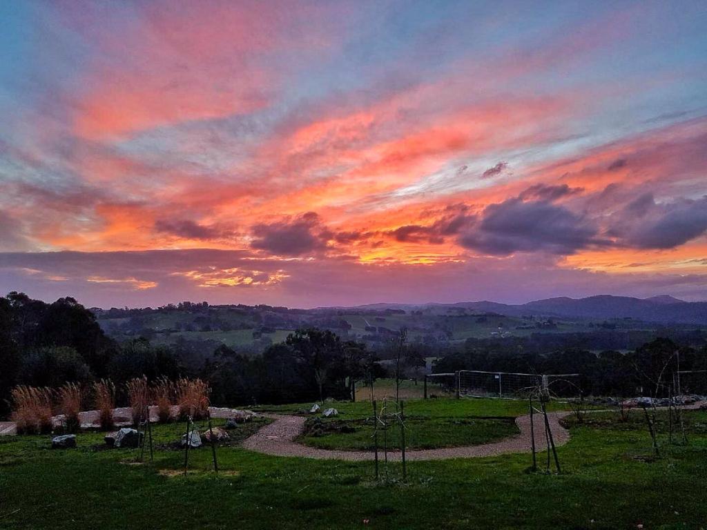 a sunset over a field with a dirt road at Vivere Retreat in Neerim South