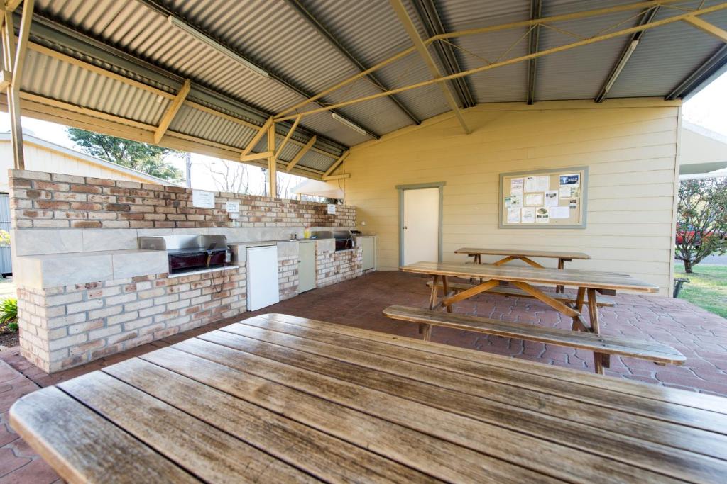 a patio with a picnic table and a grill at Fossickers Tourist Park in Nundle