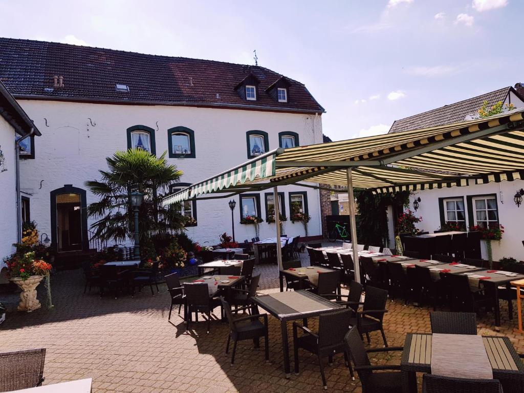 eine Terrasse mit Tischen und Stühlen und ein Gebäude in der Unterkunft Hotel Restaurant Jägerhof in Düren - Eifel