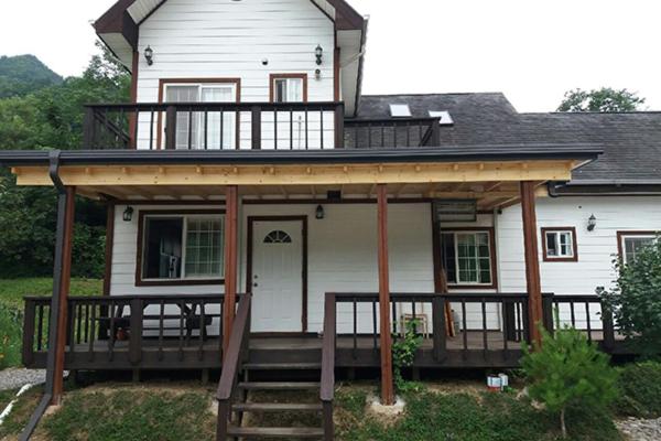 a large white house with a porch and a deck at Izmir Pension in Gangneung