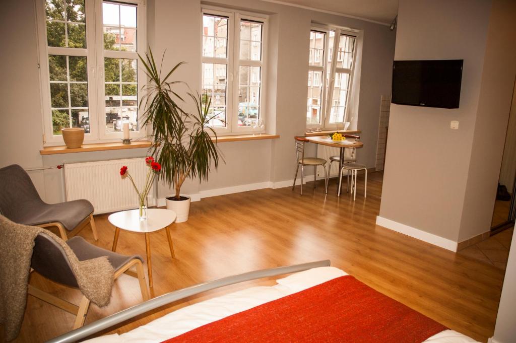 a living room with a hard wood floor and windows at Apartament - Old Town Studio in Gdańsk