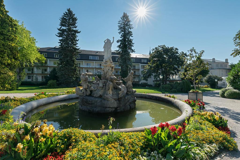 a fountain in the middle of a garden with flowers at At the Park Hotel in Baden
