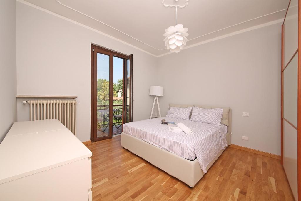 a white bedroom with a bed and a window at Casa Romeo in Sirmione