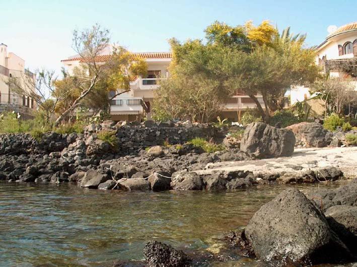 ein Fluss mit Felsen und Gebäuden im Hintergrund in der Unterkunft Villa Maria in Giardini-Naxos