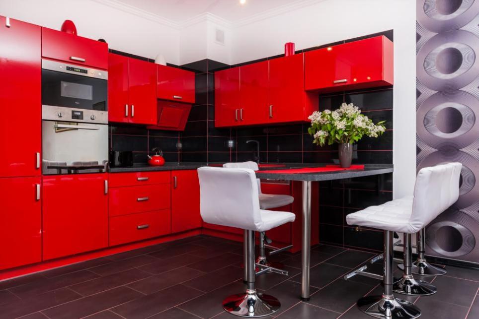 a red kitchen with white chairs and a table at Apartamenty Platan in Świnoujście