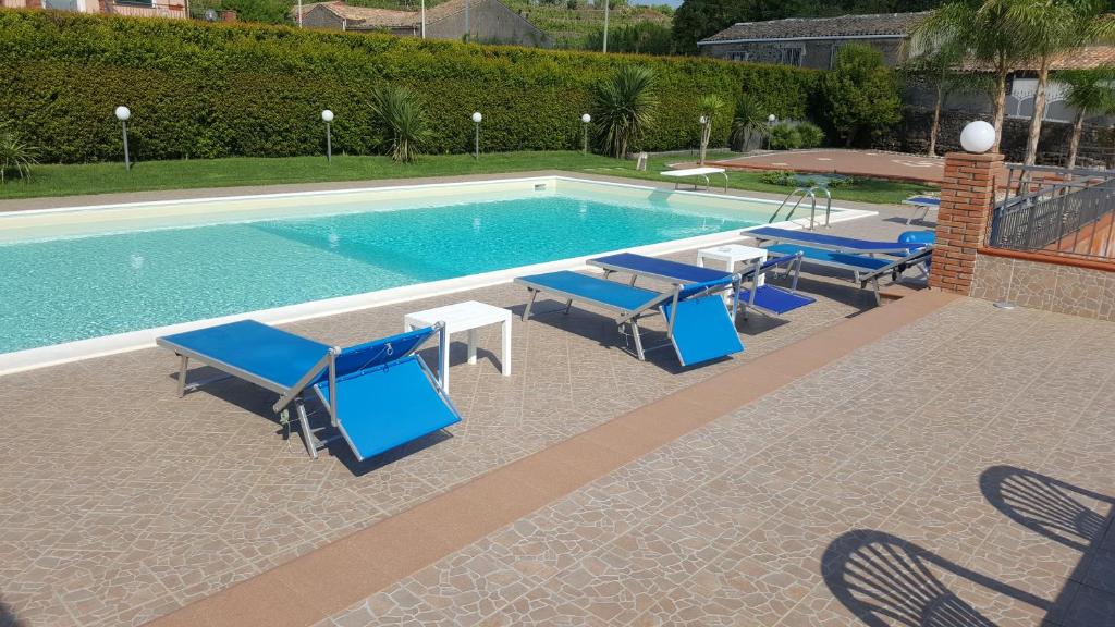 a swimming pool with blue lounge chairs and a table at Villa Etna Sea in Piedimonte Etneo
