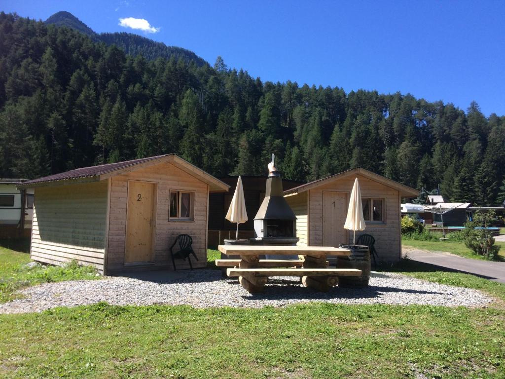 a cabin with a picnic table and umbrellas at Camping Sur En in Sent