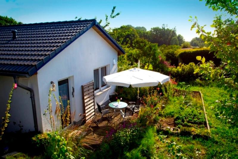 a small white house with an umbrella and a table at Ferienhaus Doris in Dwasieden