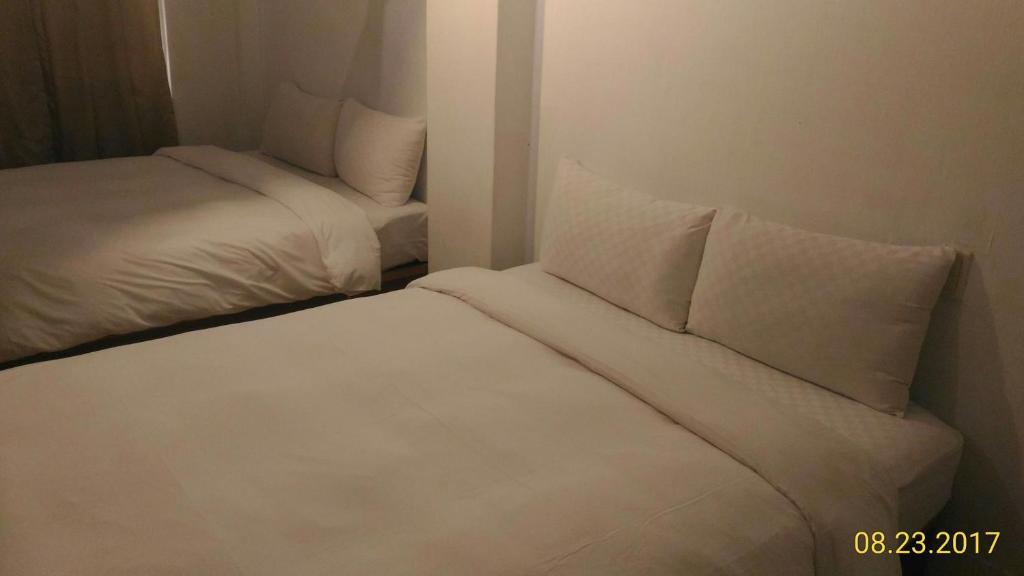 two beds in a room with white sheets and pillows at Haogong Hotel in Taichung