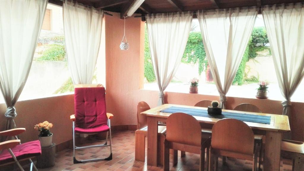 een eetkamer met een tafel, stoelen en ramen bij A Dimora di Nenè in Marina di Modica