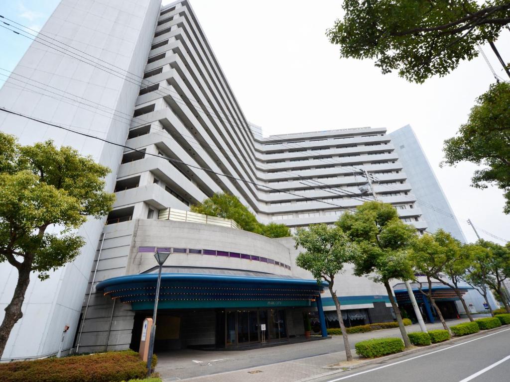 wysoki biały budynek z niebieską markizą w obiekcie Hotel Pearl City Kobe w mieście Kobe