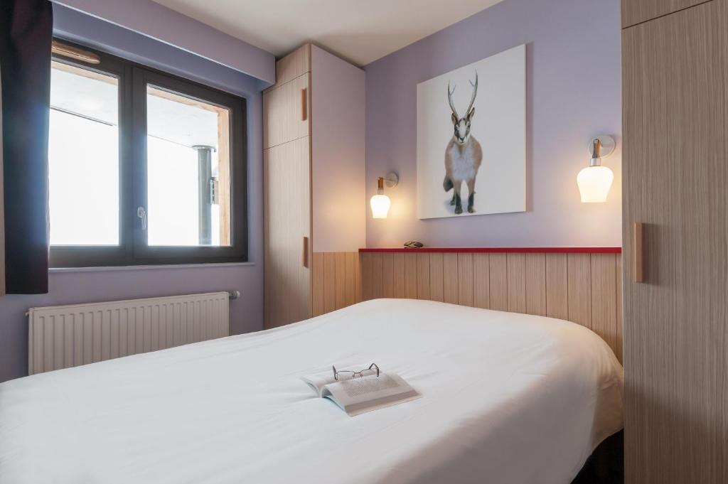 a bedroom with a white bed with a picture of a deer on the wall at Résidence Pierre &amp; Vacances Electra in Avoriaz