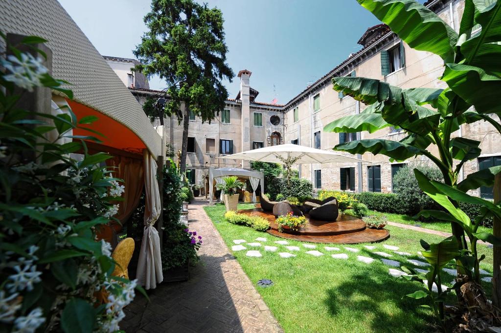 
a garden area with a patio area with a table and chairs at Hotel Abbazia in Venice
