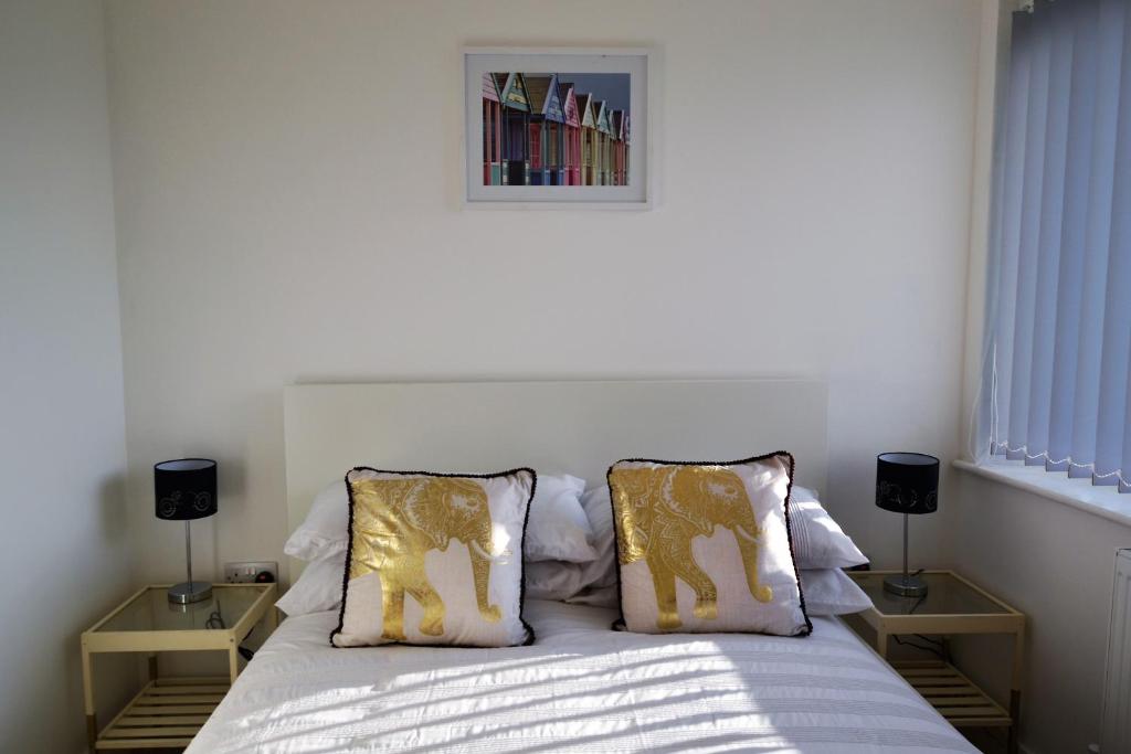 ein Schlafzimmer mit einem Bett mit goldenen Kissen und einem Bild in der Unterkunft South Coast Haven Apartments in Peacehaven