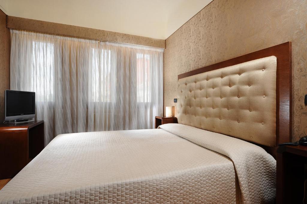 a bedroom with a large bed and a television at Hotel Abbazia in Venice