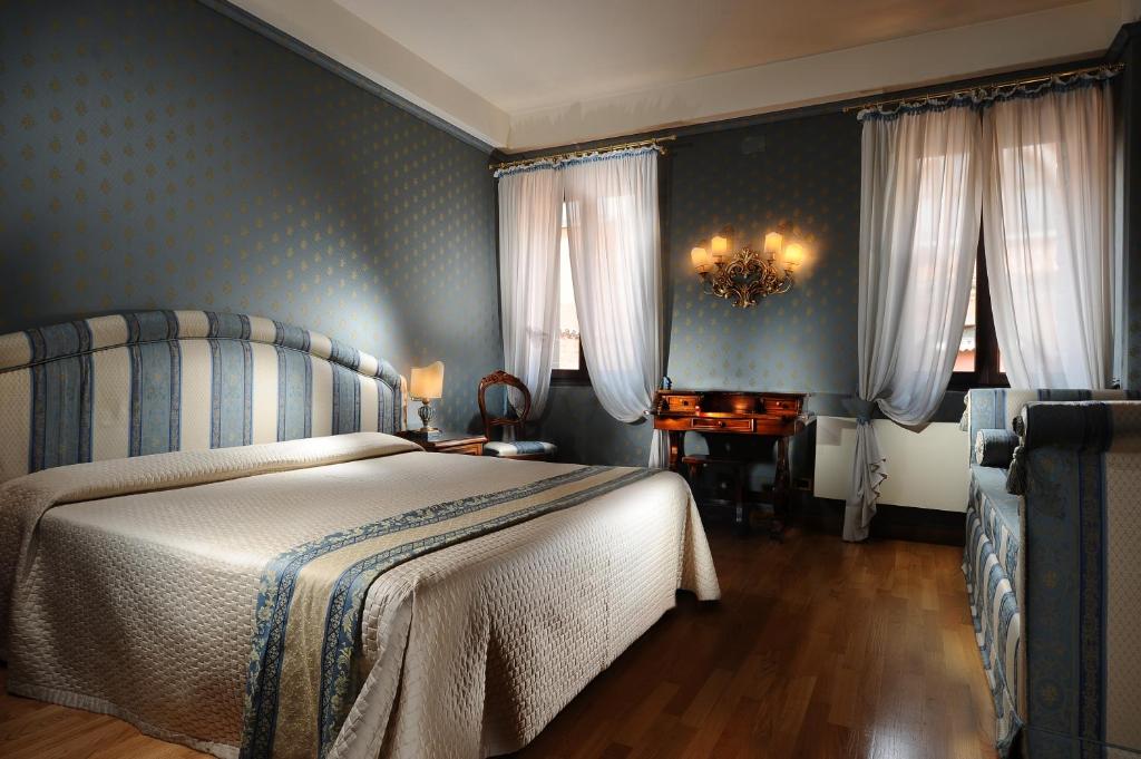 a bedroom with a bed with blue walls and curtains at Hotel Abbazia in Venice
