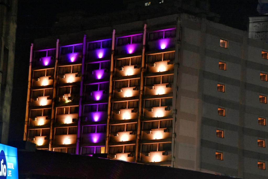 un edificio alto con luces moradas. en Hotel Poonja International, en Mangalore