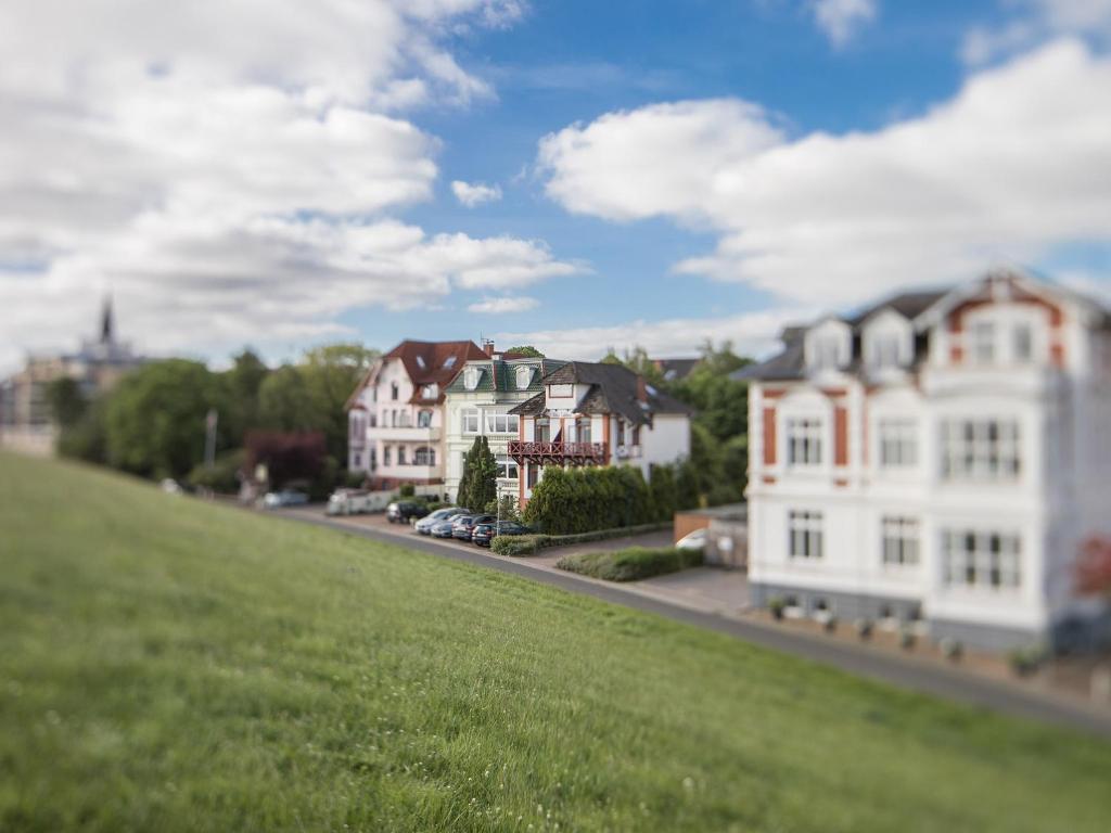 a group of houses on a street with a green field at Hotel Villa Caldera in Cuxhaven