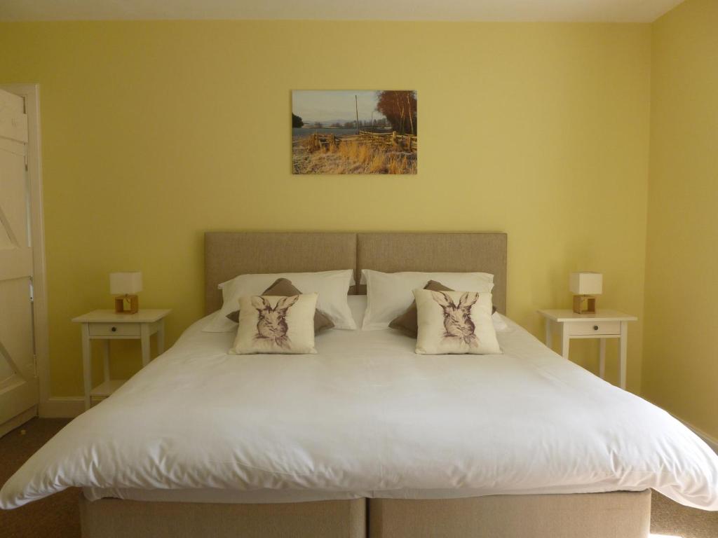 a bedroom with a white bed with two pillows at The Cottage in Etal