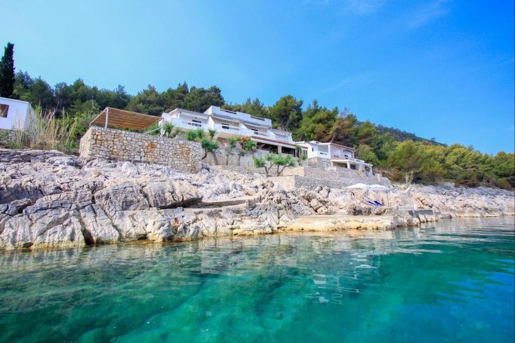 a body of water with houses on a rocky shore at Robinson Merlot in Bogomolje