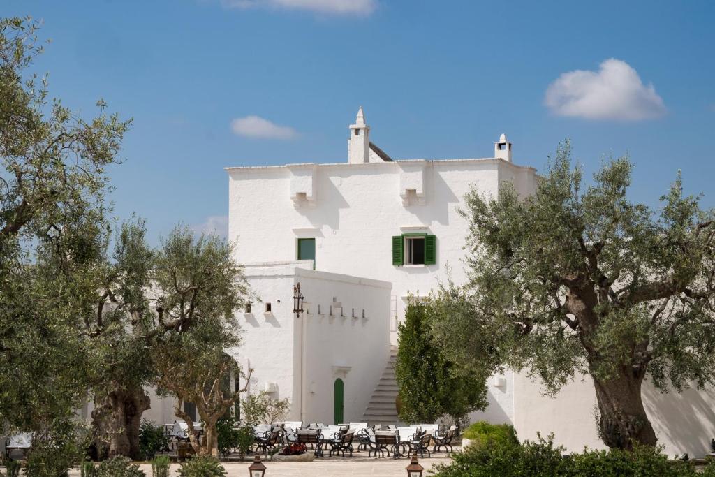 ein weißes Gebäude mit Bäumen davor in der Unterkunft Masseria Il Melograno in Monopoli