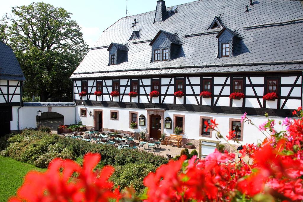 ein großes weißes Gebäude mit roten Blumen davor in der Unterkunft Hotel Folklorehof in Chemnitz