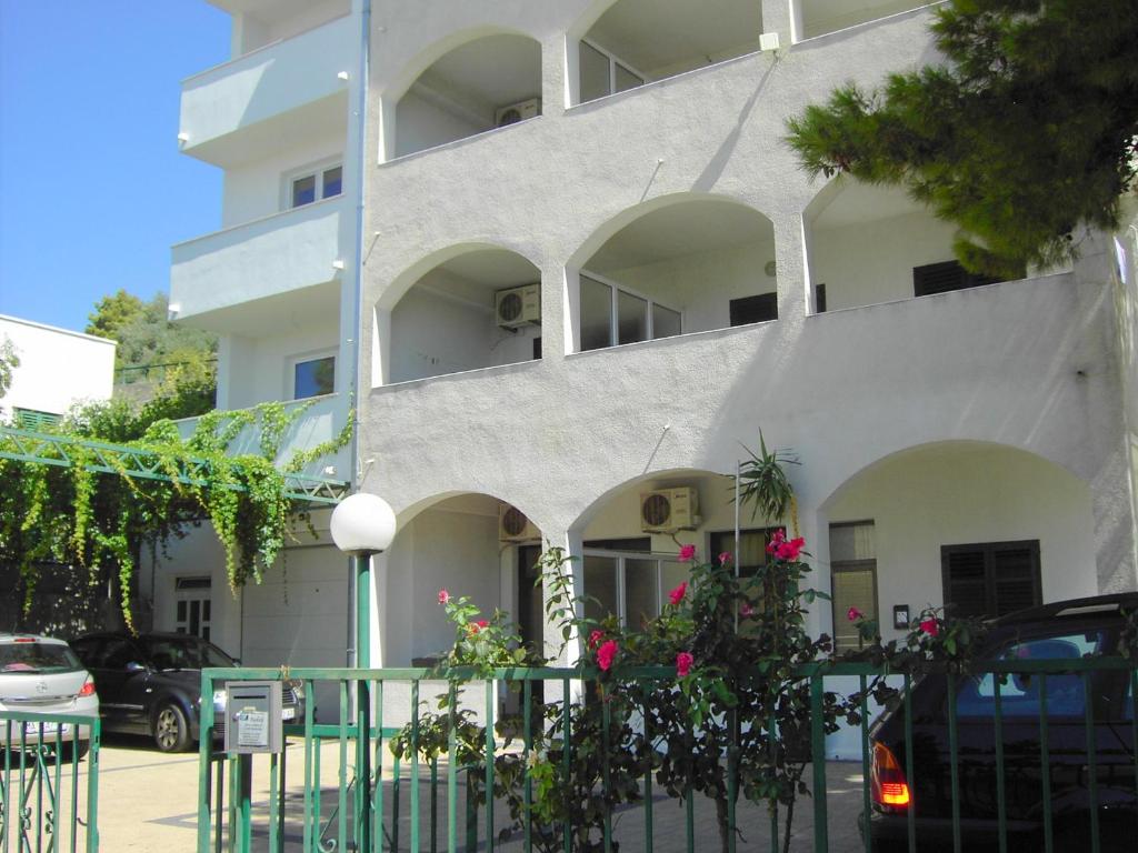 a white building with pink flowers in front of it at Apartmani R&B Radalj in Makarska