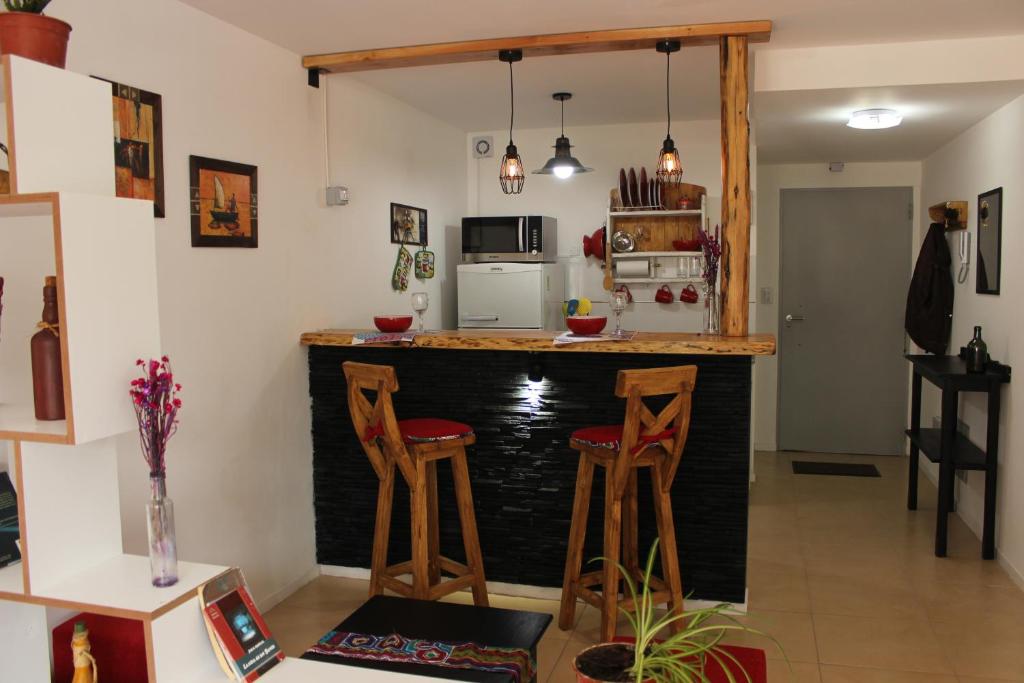 una cocina con una barra con dos taburetes en El Escaramujo en San Carlos de Bariloche