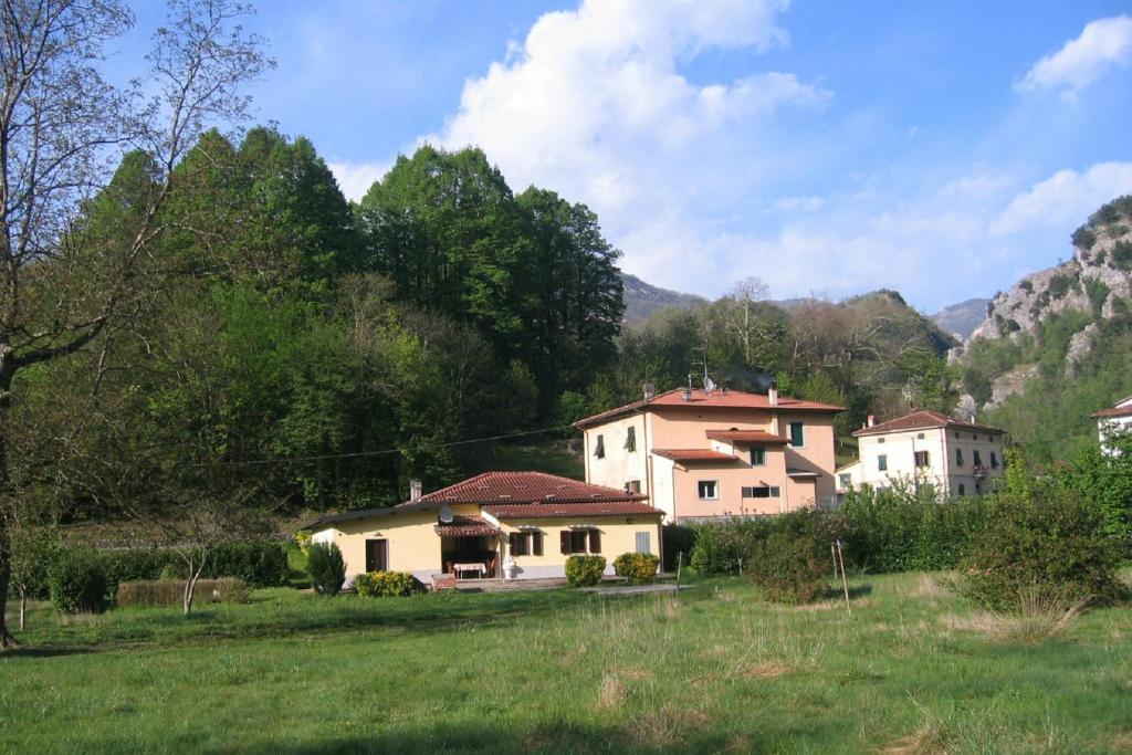 um grupo de casas num campo com montanhas ao fundo em Villa with River Access em Cocciglia