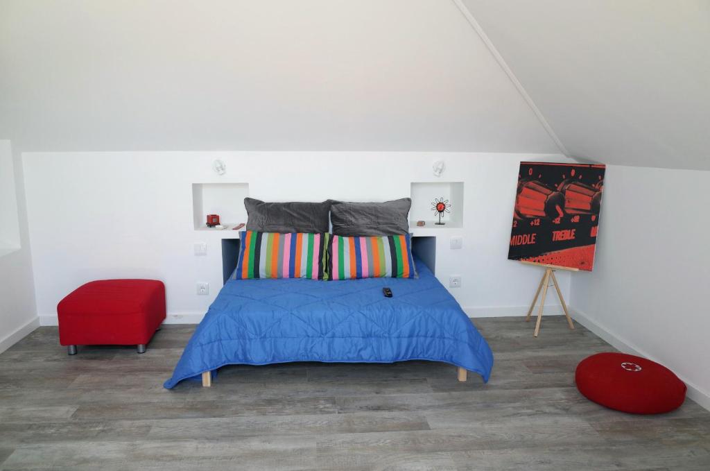 een slaapkamer met een bed en een rode stoel bij Lisbon Beach Apartments 5 in Costa da Caparica