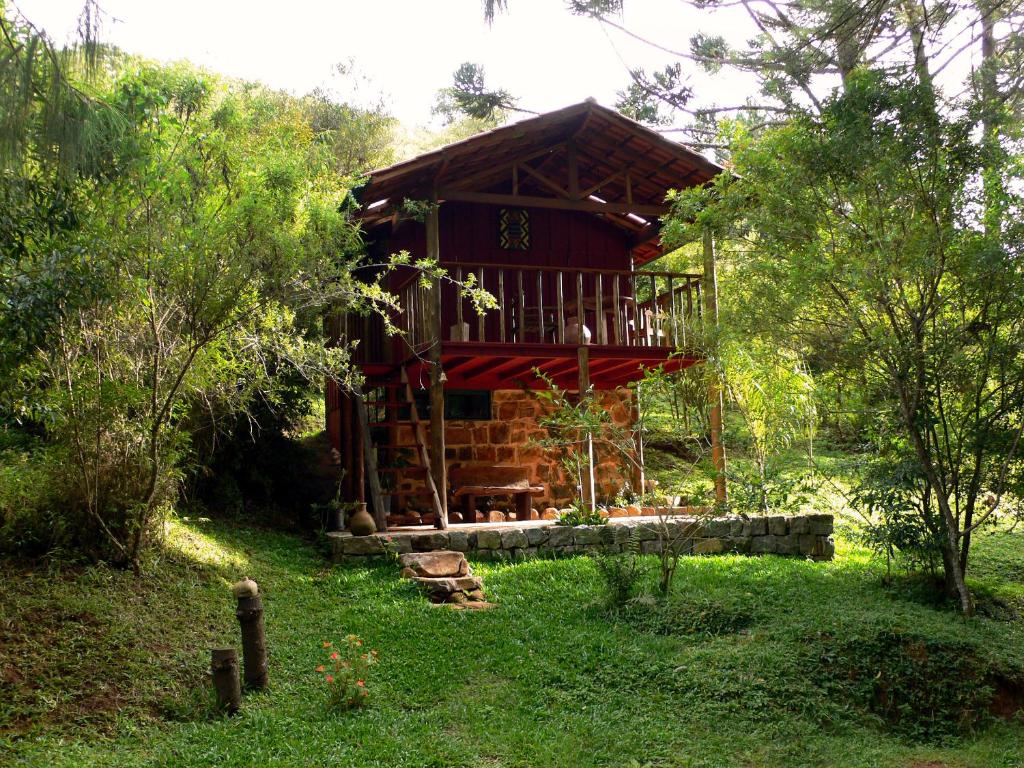 une cabane en rondins au milieu d'un champ planté d'arbres dans l'établissement Pousada dos Anjos, à Cunha