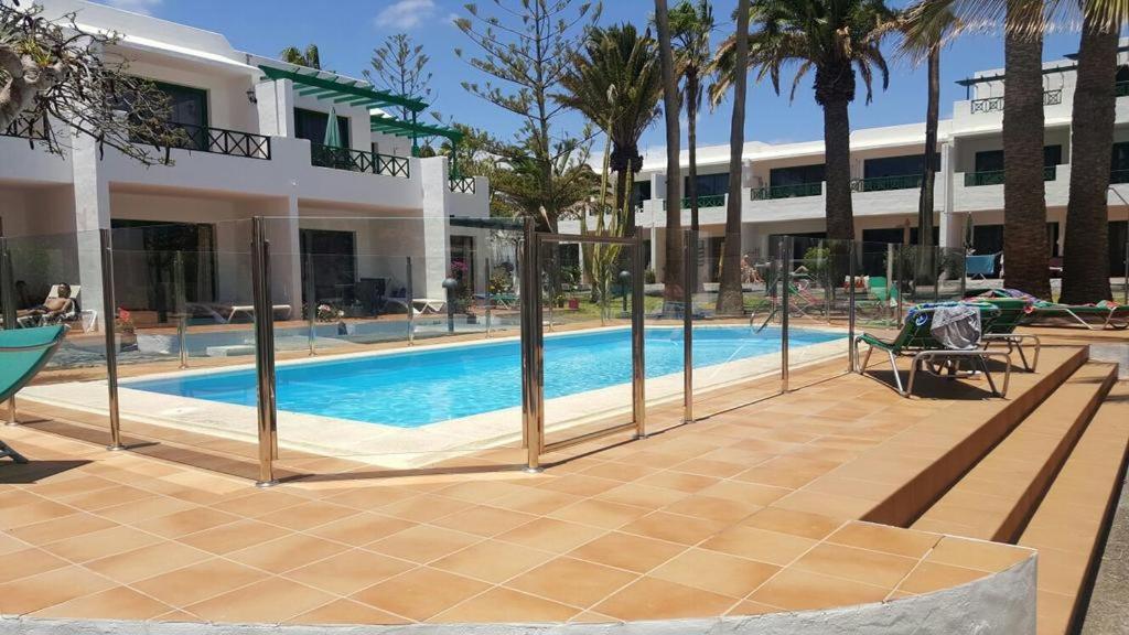 una piscina di fronte a un edificio con palme di Paradise Club Oasis a Puerto del Carmen