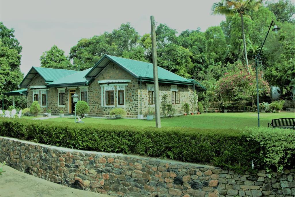 a stone house with a green roof and a stone wall at Sithara Estate Bungalow in Ella